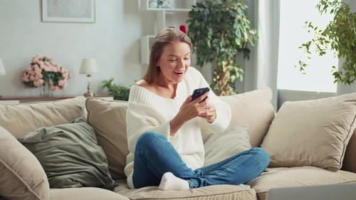 Excited Woman Relaxing at Home with Phone