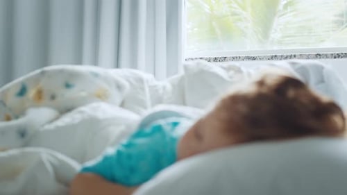 Das Kind schläft. Ein kleines Mädchen schläft im hellen, modernen Schlafzimmer. Fokusständer vom Fenster zum Kind