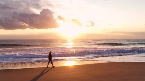 Cinematic View of the Seascape A Man Walks Along the Beach Slow Motion Looks at the Sunset the Waves
