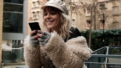 Modelo femenina que usa el teléfono en un entorno urbano.