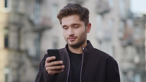 Attractive Young Man Uses Phone in City Environment