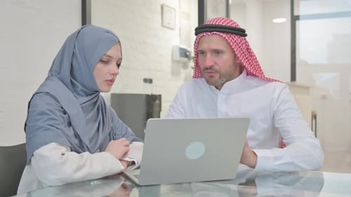 Woman in Hijab and Man Collaborating on Laptop