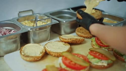 Tasty Close Up Footage of a Cook Preparing Burgers. Food Chef is Adding Souce on top of Buns with S
