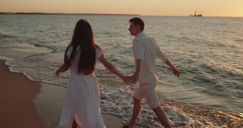 Young Loving Couple Enjoying Relaxing Sunset Walk on the Beach