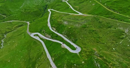 Aerial View of Tourists on Road Trip Across the Mountains of Switzerland Drive Along Hairpin Turns