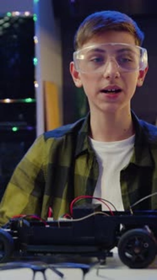 Teen Boy Soldering a Toy Car in Workshop