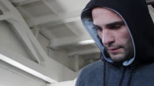 Tired Man in Hooded Jacket Relaxing While Walking at Healthcare Center