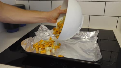 Arm Pouring Chopped Vegetables onto a Foil Baking Sheet