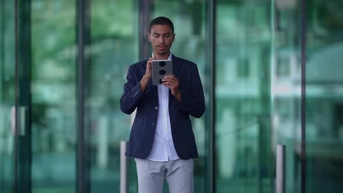A Successful Businessman is Utilizing a Tablet in a Contemporary Urban Business Setting
