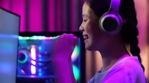 Close Up Of Excited Asian Teen Girl Gamer Celebrates Victory While Playing Video Game On Computer