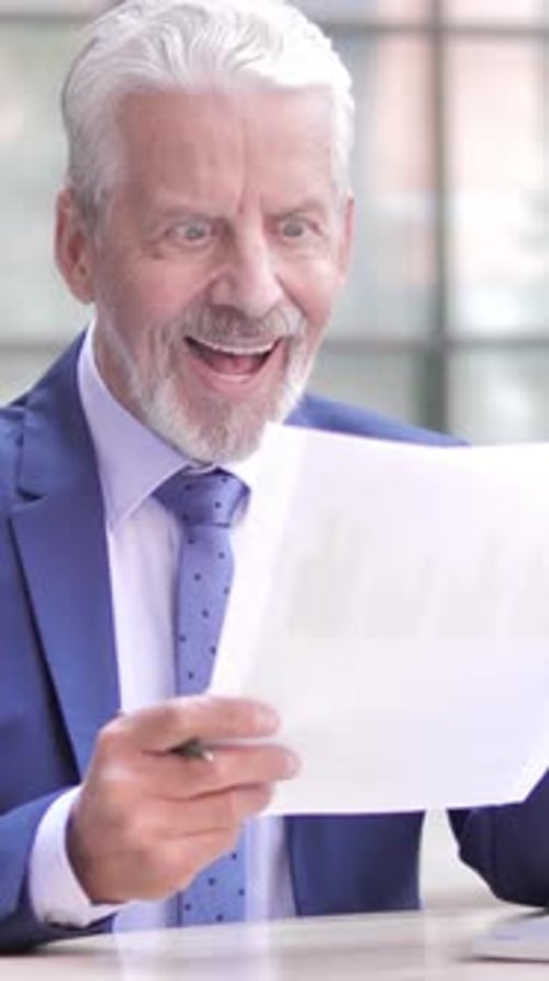 Happy Senior Businessman Reads Positive Financial Report