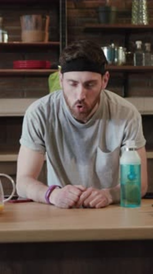 Man Rubs Face While Sitting Indoors