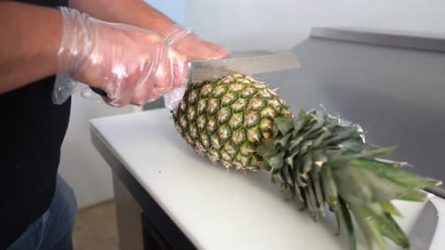 Person Cutting a Pineapple on a Cutting Board