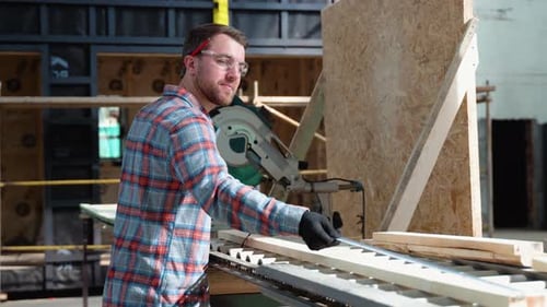 Building Contractor Worker Using Hand Held Worm Drive Circular Saw to Cut Boards on a New Home