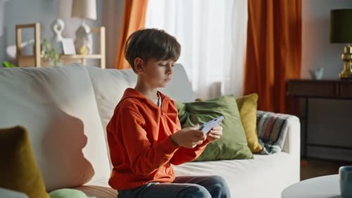 Happy Boy Playing Game on Mobile Phone Indoors