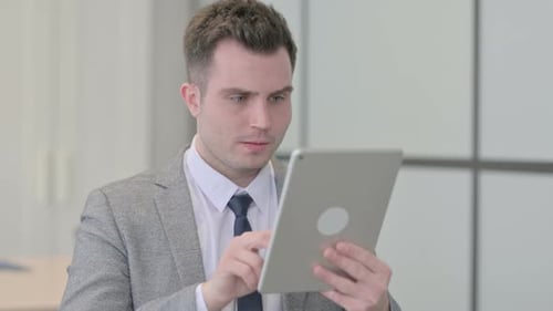Young Adult Using Tablet in Office Appears Upset