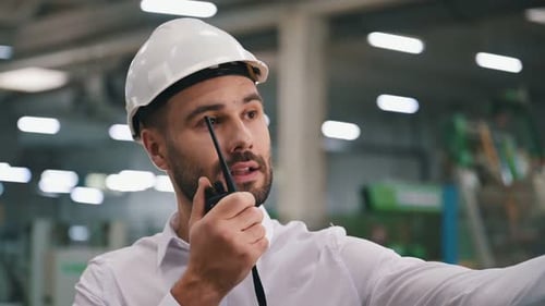 Nahaufnahme beim Sprechen mit einem Walkie-Talkie. Der Mensch arbeitet in der modernen Fabrik.