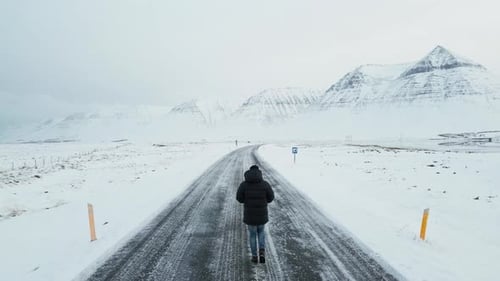 Man Walking On A Road With Snowy Mountains In View