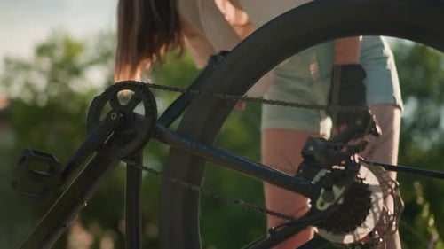 Woman Fixing Bike Chain Outside on Sunny Day