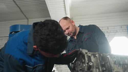Ingénieurs travaillant sur l'assemblage du moteur dans un atelier automobile