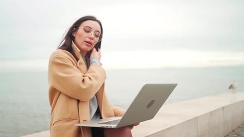 Geschäftsfrau im eleganten Mantel benutzt Laptop im Freien