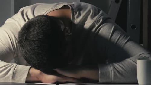 Exhausted Man Resting Head on Desk at Night