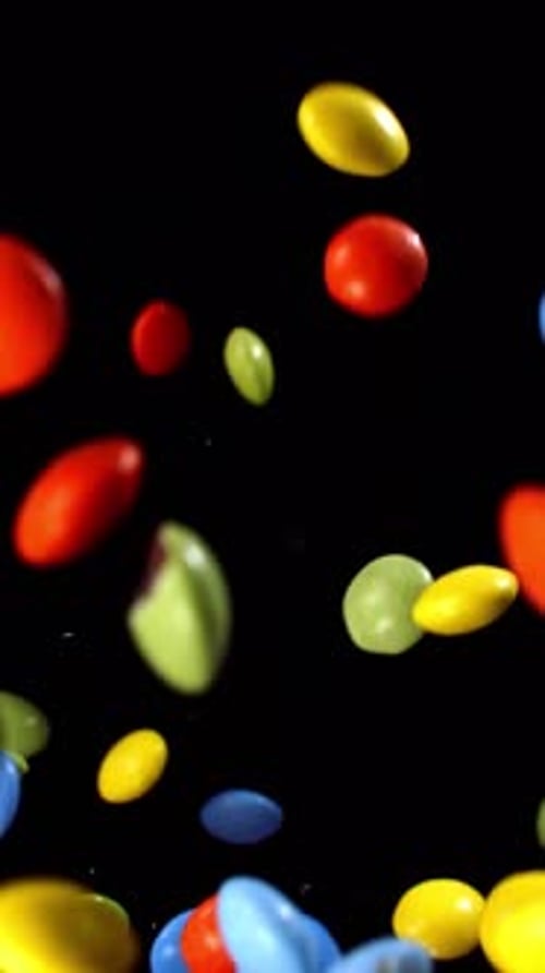 Colorful Candy Pieces Floating Upwards on Black