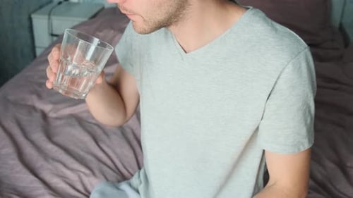 Young Adult Male Taking Pill with Water