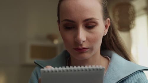 Woman Writing in Notebook at Home Daytime