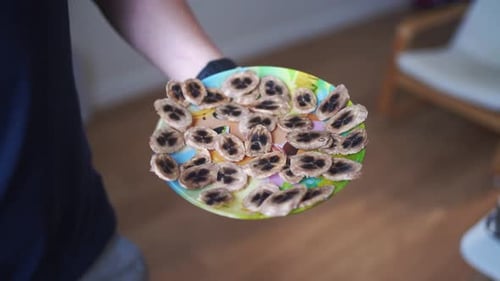 Presentar a mano un colorido plato de plátanos secos, una opción de refrigerio saludable