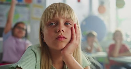 Close Up of Sad Primary School Girl Sitting at Desk Getting Tired During Lesson