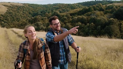 Couple Hiking Through Grassy Hills with Backpacks