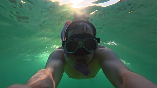 A Man Wearing a Mask and Snorkel Swims Underwater in the Ocean Exploring the Underwater World and