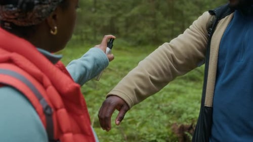 Woman Sprays Man With Insect Repellent in Forest