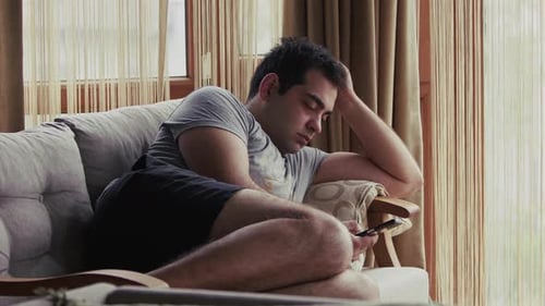 Man Lounging on Couch Using Smartphone