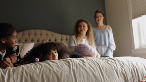 Teen Girls Laughing on Bed Together Indoors