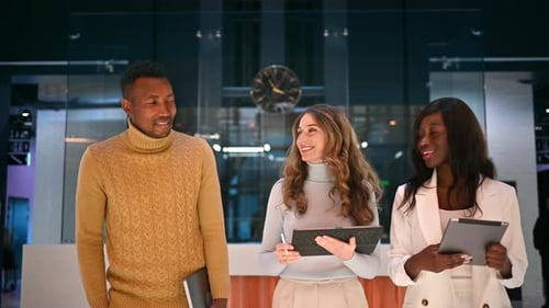 Multiracial group of workers in an office walking and discussing business using tablets