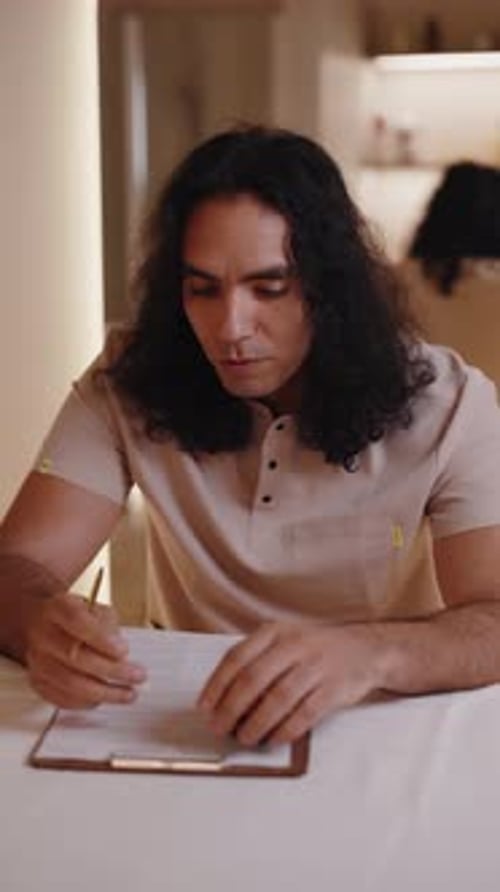 Man Filling Out Form on Clipboard at Table