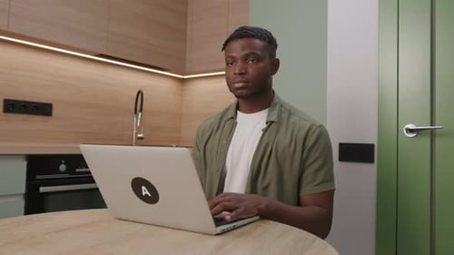 Young Adult Typing on Laptop in Modern Kitchen