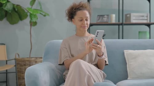 Woman Relaxing on Couch Using Smartphone at Home