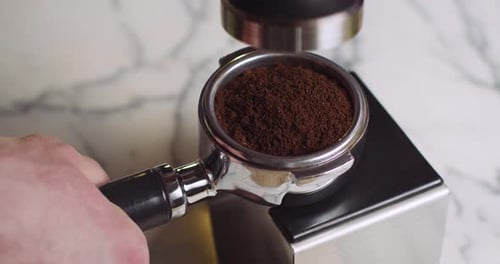 Barista stopft und drückt Espresso-Kaffee auf einem Siebträger mit Metallstampfer herunter und serviert ihn