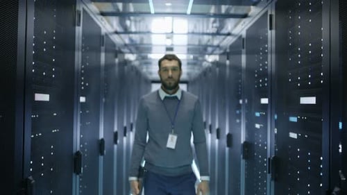 IT Engineer Walks Into Focus and Smiles in Data Center Full of Rack Servers.