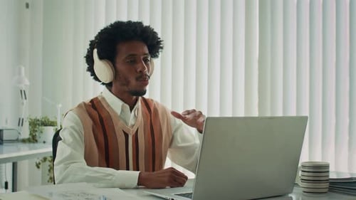 Black Entrepreneur Talking on Video Using Laptop at Office Desk