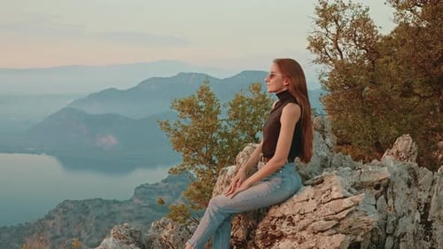 Side View Free Happy Young Female Traveler Wearing Sunglasses Sits on Rock on