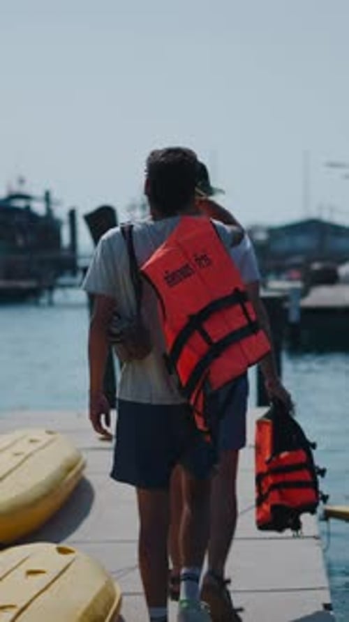 Two Friends Prepare for a Kayaking Adventure on a Lakeside Dock