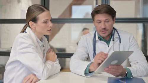 Doctor Discussing Medical Report on Digital Tablet with Female Doctor