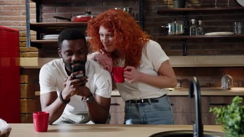 Happy Couple Looking at Phone in Kitchen