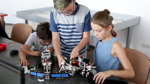 Group of Happy Kids with Laptop Computer Building Robots at Robotics School Lesson