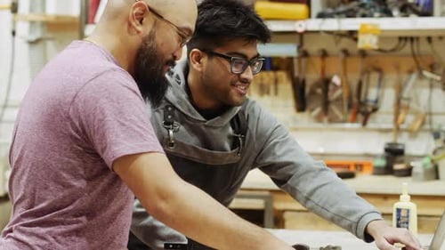 Male Carpenters Working Together At Laptop In Workshop Slow Motion