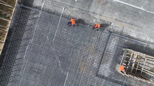 Luftaufnahme: Bauarbeiter biegen Bewehrungsstahl für tragendes Fundament